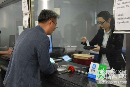 中国侨网4月8日，一位侨胞在休斯敦总领馆成功的用微信支付的方式完成了办证缴费 （侨报记者陈琳摄）