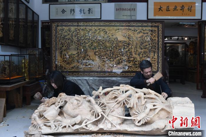 图为陈嘉和父亲陈培希一起制作大型木雕作品《龙虾蟹篓》 陈楚红 摄