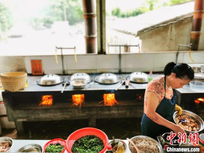 服务员在柴火灶前对处理好的鸡块调味、腌制 李晓春 摄