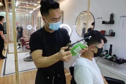 许启荣在三阶段重启后帮顾客理发。(美国《世界日报》/张晨 摄)