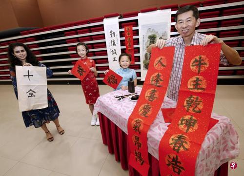 中国侨网来自印度的莎睿涵(左起)、宋家瑛和妹妹宋家娴，以及2021年N立方全国书法大赛最年长参赛者洪广和，一起展示他们的作品。（新加坡《联合早报》/梁麒麟 摄）