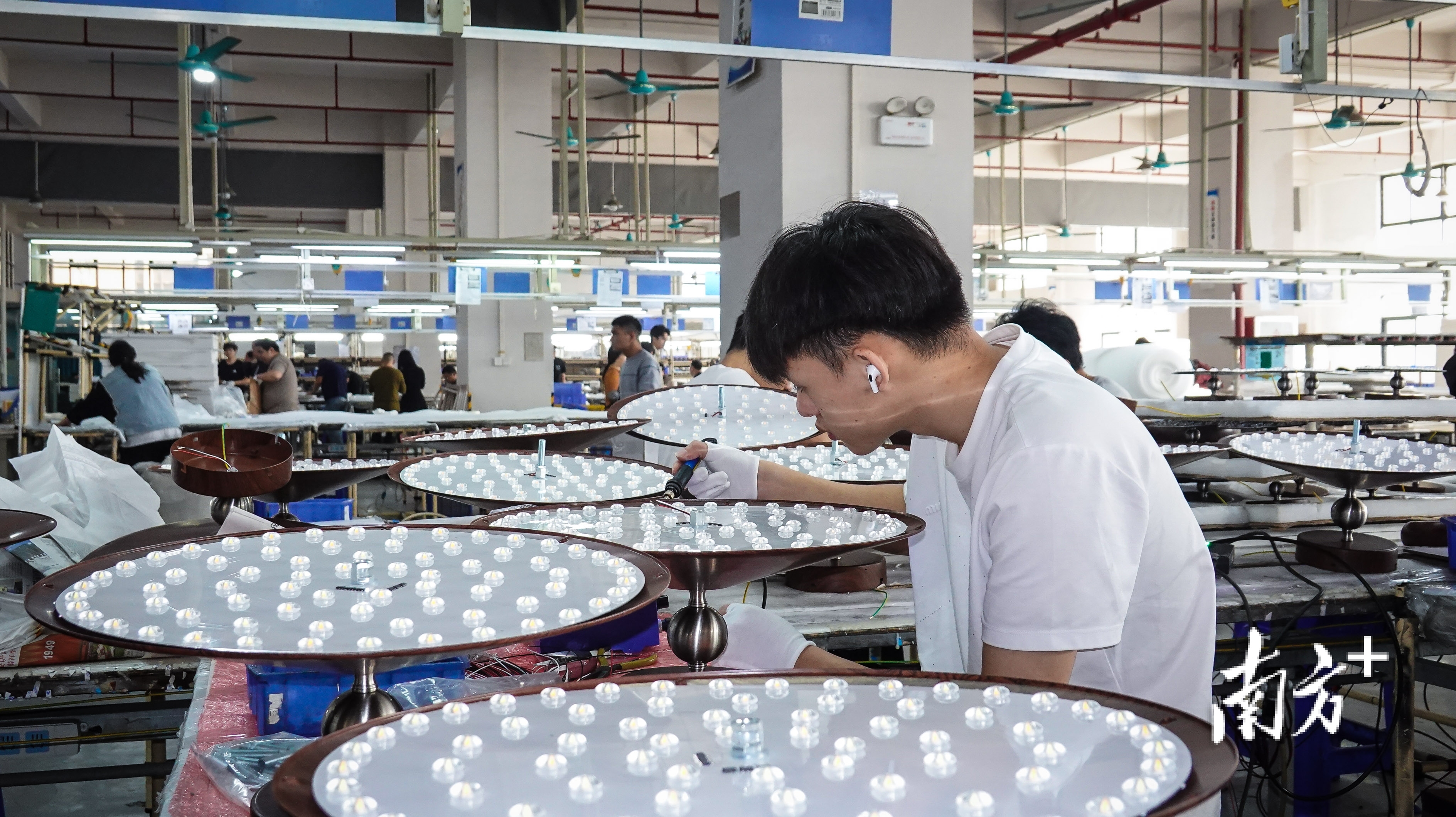 中山市海弗来照明科技有限公司车间内,工人正在对灯饰进行装配作业。