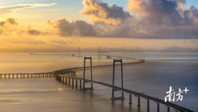 朝阳照射在深中通道上，勾勒出远处城市群的轮廓。