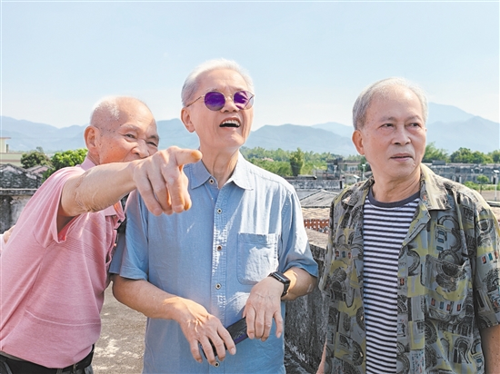 伍爵彬（中）与伍加尧（左）、伍加强（右）在祖屋屋顶眺望家乡景色。